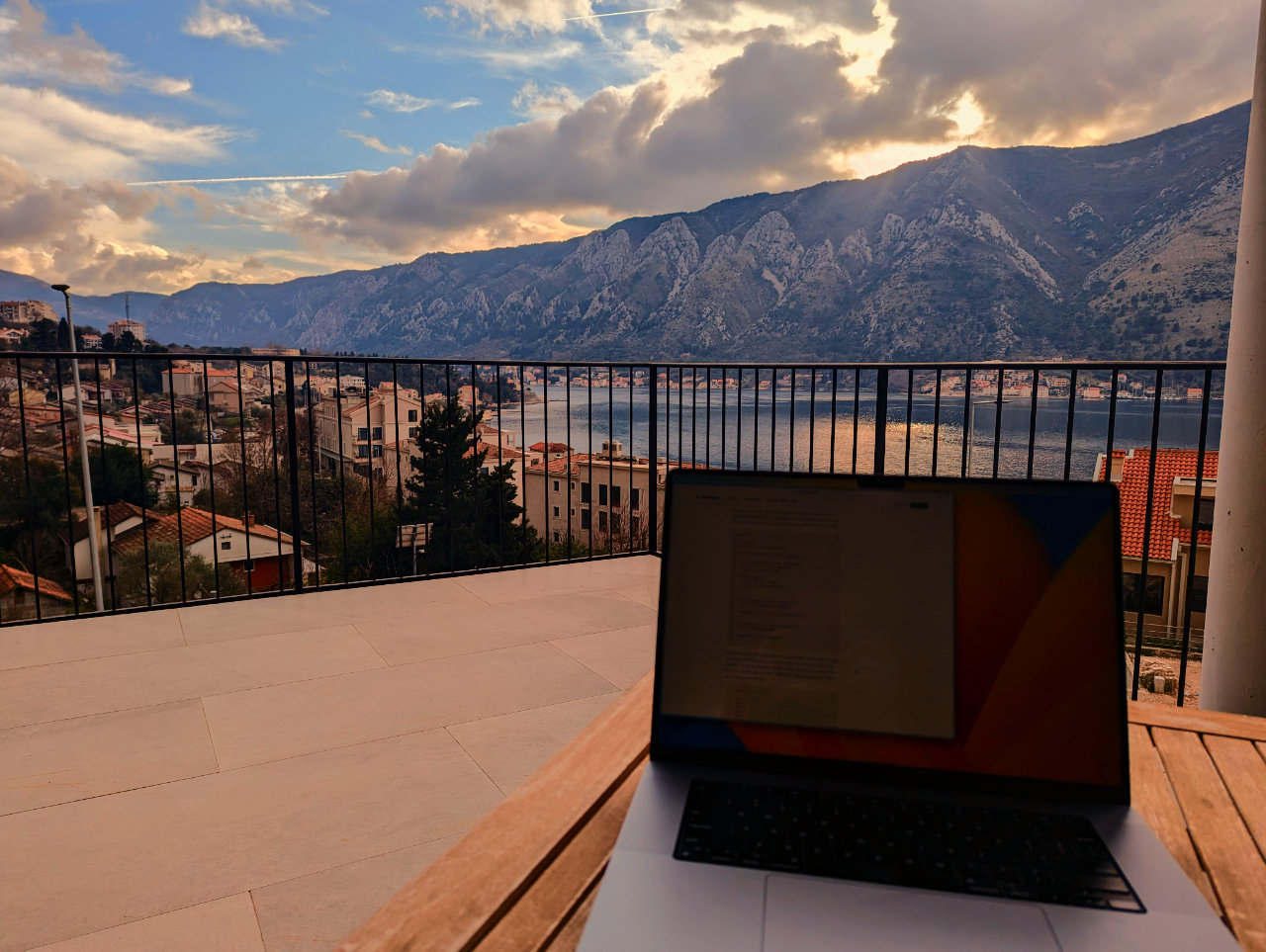 laptop open on a balcony with a view of Kotor Bay, Montenegro
